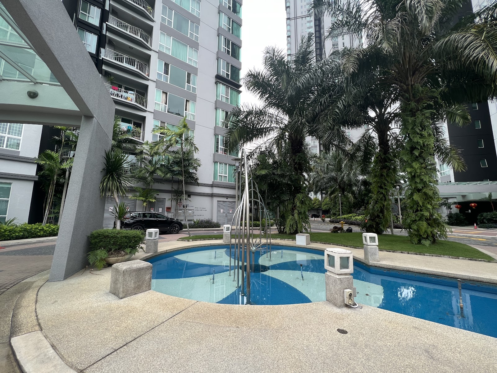 Kiaramas Ayuria: Swimming pool with fountain jets surrounded by palm trees and residential towers in a condominium compound