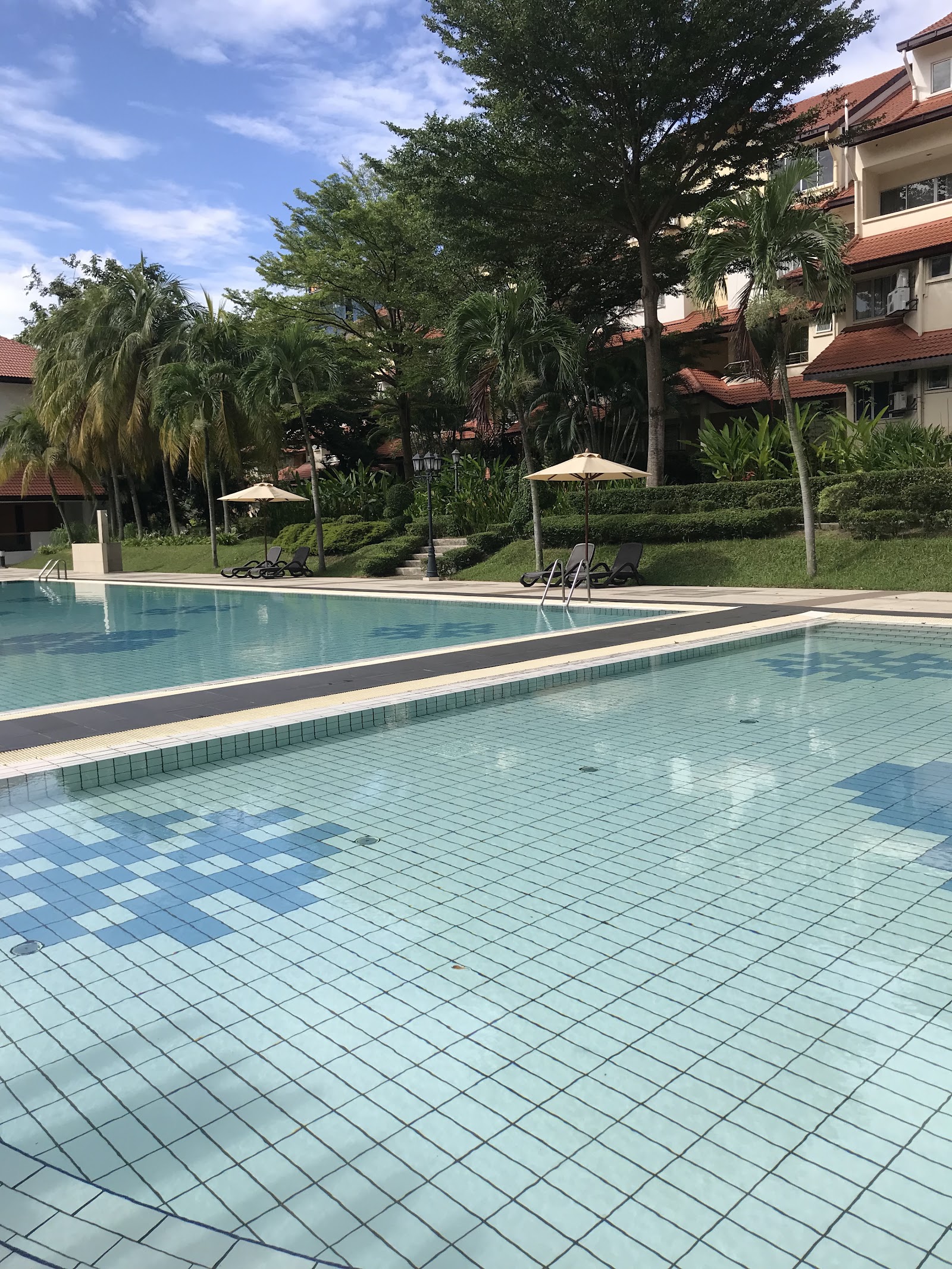 Villa Flora: Swimming pools with lounge chairs, umbrellas, and palm trees at a residential development