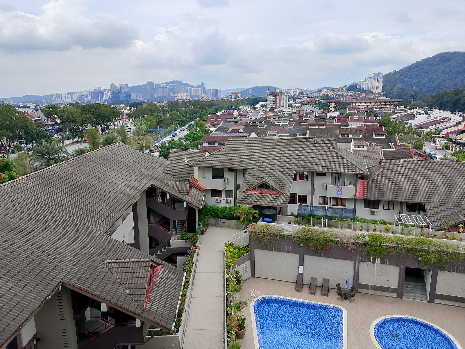 Trellises: Aerial view of a residential complex showing rooftops, a swimming pool area with loungers, and surrounding cityscape and hills