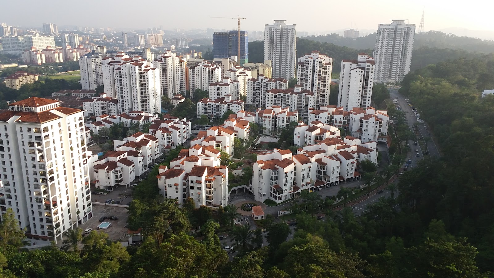 Andalucia: Aerial view of a residential condominium complex with red-roofed low-rise buildings surrounded by high-rise towers and trees, near a road