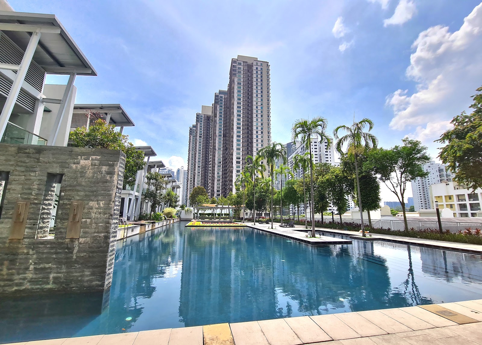 Kiara Designer Suites: Outdoor swimming pool surrounded by palm trees with high-rise condominium towers in the background