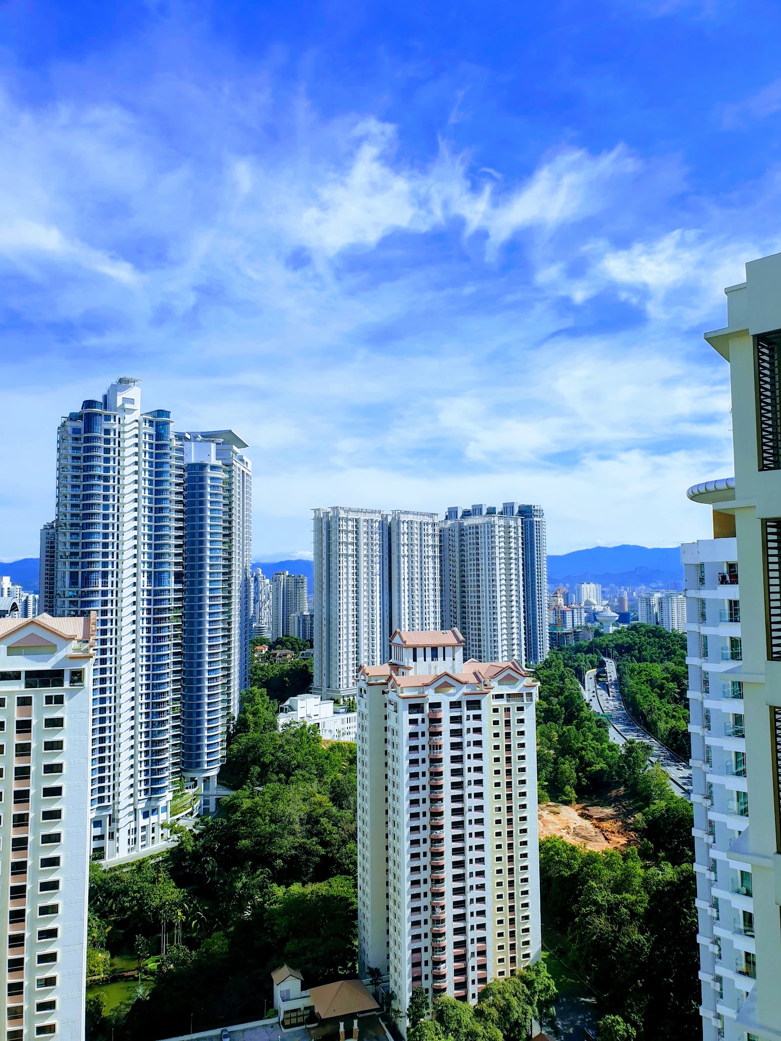 i-Zen @ Kiara 2: A high-rise view of surrounding city skyline with numerous condominium towers, greenery, and mountains in the distance, taken from a high floor balcony