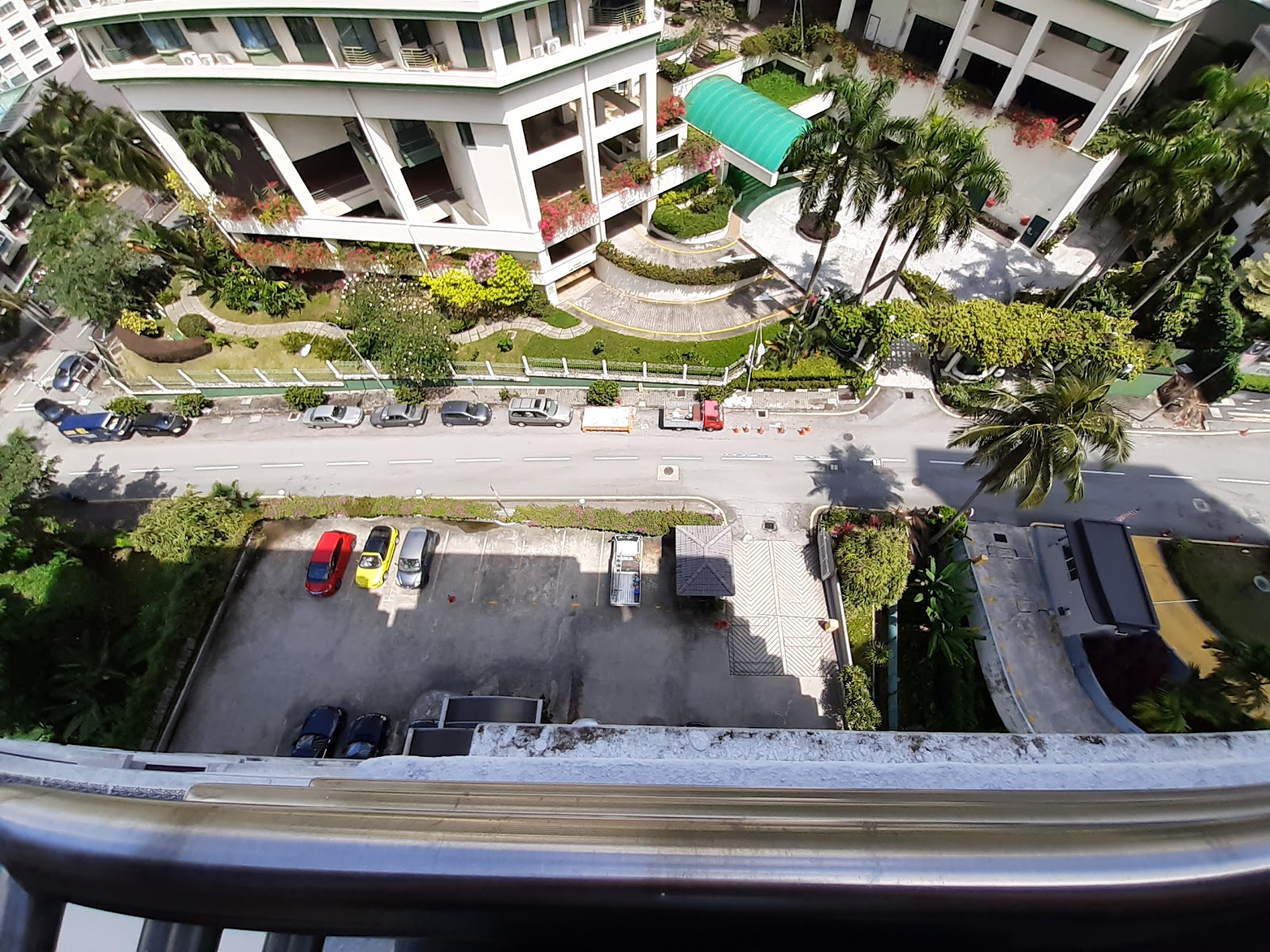 Park Rose: Aerial view down from a high balcony showing a parking lot, road, landscaped gardens and part of a low-rise building complex below