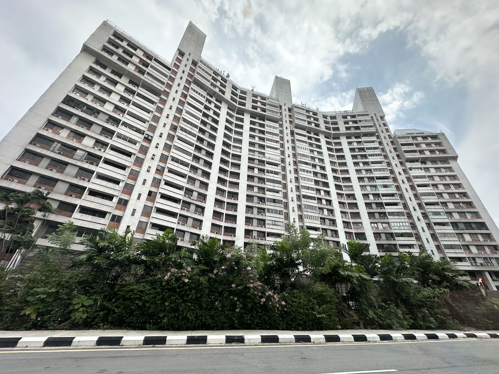 Sri Wangsaria: High-rise residential apartment building facade viewed from street level with greenery in foreground