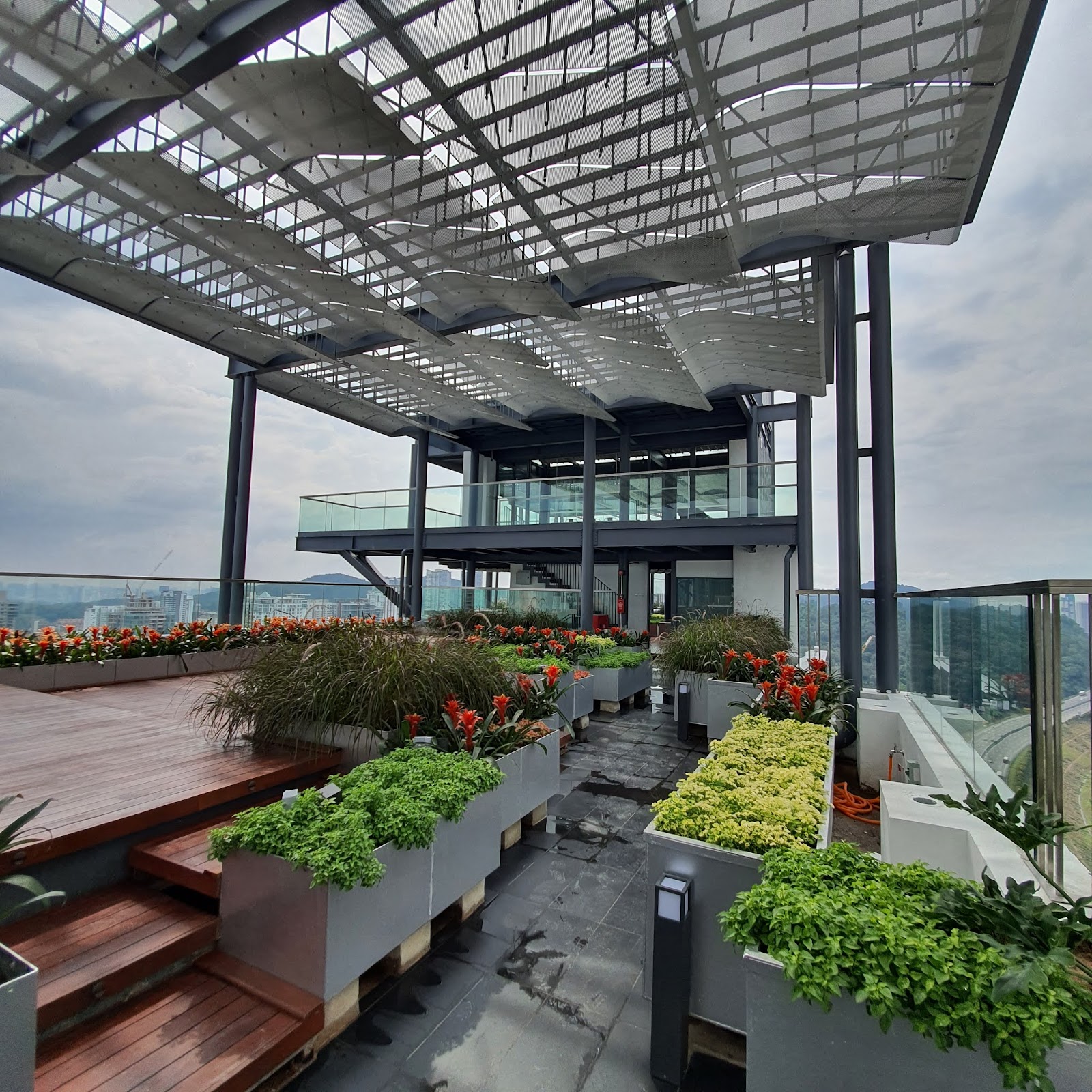 TWY Mont Kiara: Rooftop garden terrace with planters, flowers, wooden deck, and a pergola structure overlooking the city skyline